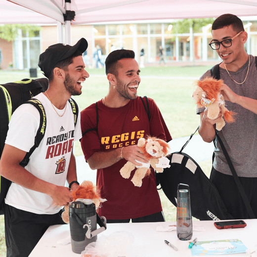 3 Regis students laughing while participating in Stuff-A-Lion