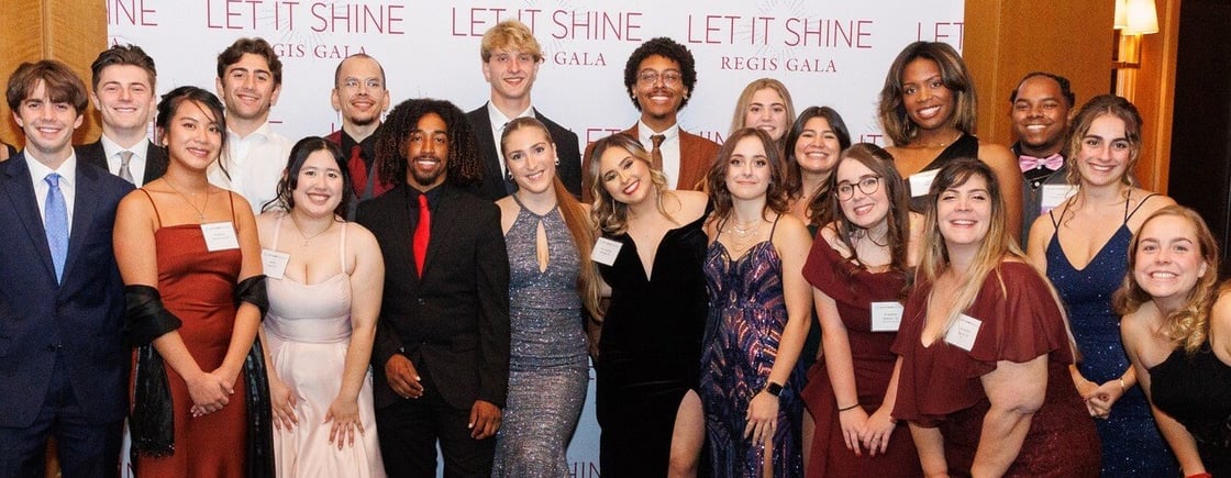 Regis students in formal attire pose for a group photo at the Let It Shine Gala