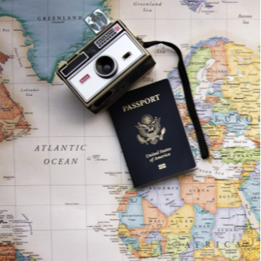 A camera and passport on top of an atlas