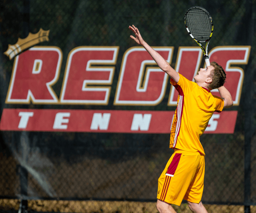 Male tennis player serving a tennis ball on the Regis court