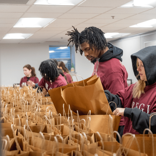 Regis volunteers sort donations in brown paper bags