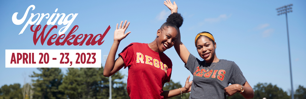 Two smiling students waving to the camera in Regis gear