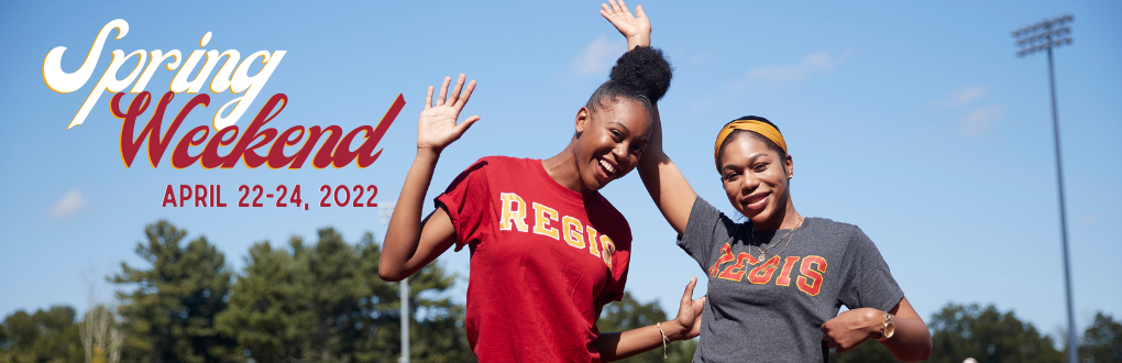 two students in Regis t-shirts smiling and waving at the camera with the Spring Weekend logo typed against the sky