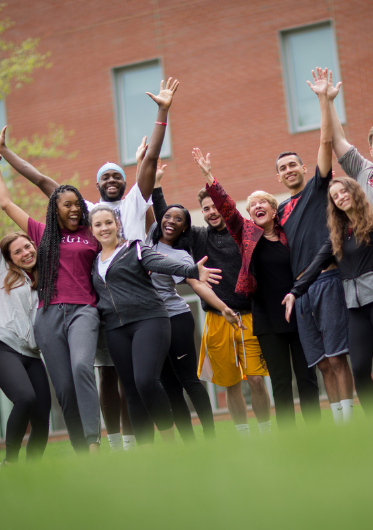 A group of students wearing Regis apparel and smiling on the Quad